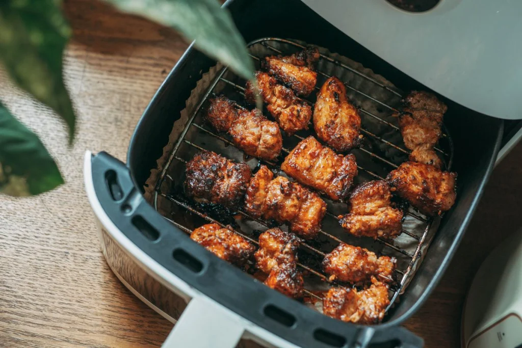 Geopende airfryer-mand met krokant bereide stukken vlees