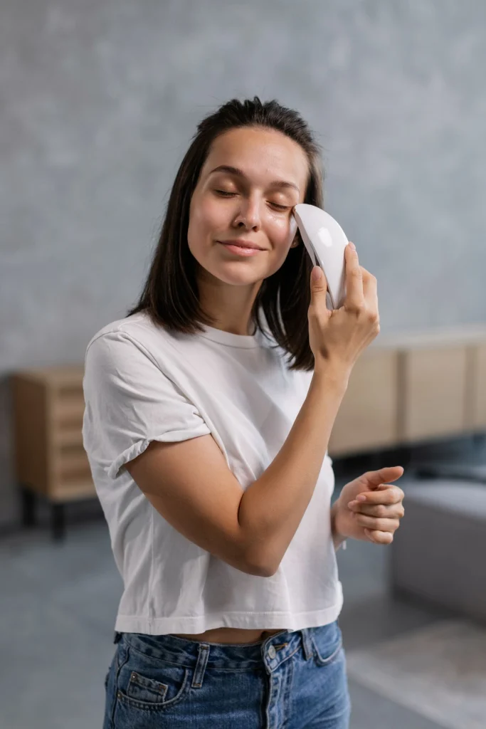 Vrouw gebruikt een handzaam EMS-gezichtsapparaat voor huidverzorging thuis
