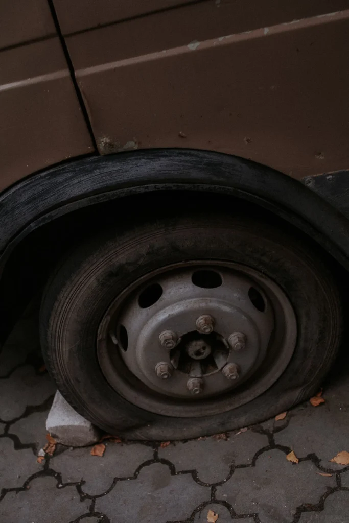 Lekke autoband met platte band tegen het voertuig, close-up van het wiel