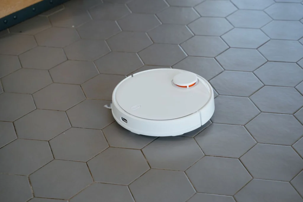 Ronde witte robotstofzuiger op een hexagonale tegelvloer