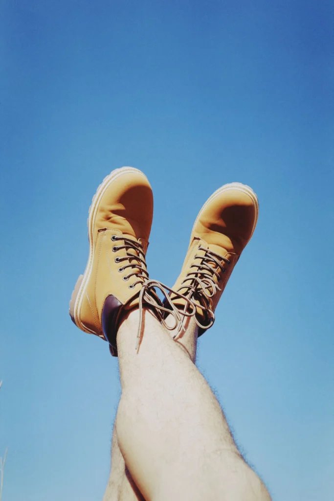 Wandelschoenen aan de voeten tegen een heldere blauwe lucht